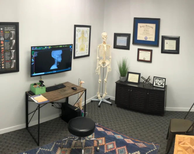 chiropractic room with beige walls, a few frames and a computer in the center of the room